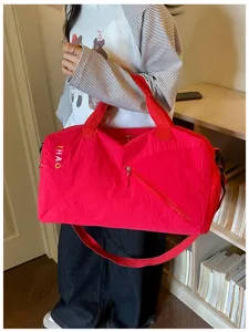 Detalles de la bolsa de viaje roja con correa, bolsillo lateral y tejido resistente.