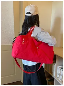 Vista detallada de la bolsa de viaje roja con bolsillo con cremallera y correa.