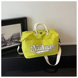 Detalle de bolsa de viaje verde lima con llamativo estampado de letras y asas blancas.