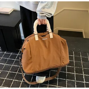 Detail view of large capacity brown travel duffel bag, showcasing durable fabric and sturdy handles.