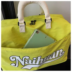Bolsa de viaje verde con asas blancas y bolsillo delantero para desplazamientos y viajes.