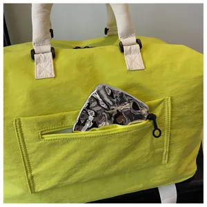 Bolsa de viaje amarilla con asas blancas y bolsillo frontal para viajes cortos.