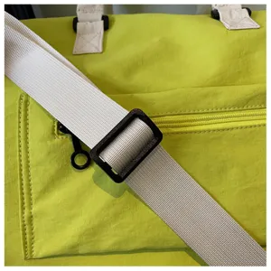 Primer plano detallado de bolsa de viaje verde con correa blanca ancha, hebilla y bolsillo.