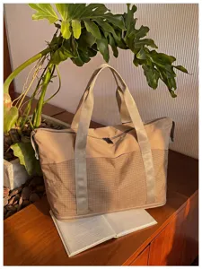 Detail view of large capacity beige travel tote bag with durable grid bottom and dual handles.