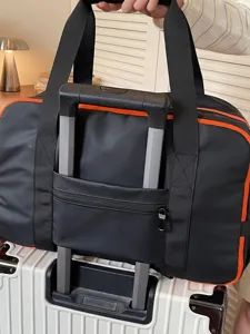 Fashionable black orange travel duffel bag with trolley sleeve for short trips boarding.