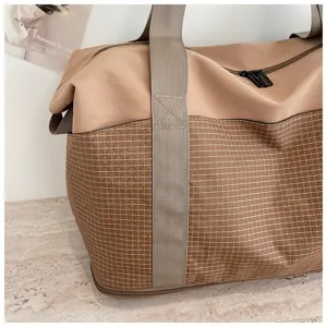 Travel duffel bag detail showing durable waterproof fabric, sturdy handles and bottom zipper expansion.