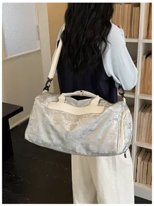 Sac de voyage argenté froissé avec poignées en cuir blanc pour le sport, les trajets et voyages.