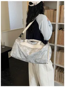 Sac de voyage argenté élégant avec bandoulière, idéal pour les courts séjours et trajets.