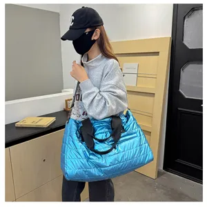 Metallic blue puffer travel bag lifestyle detail shot, stylish large capacity tote.