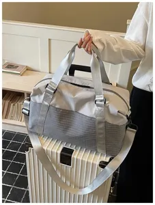 Detailaufnahme der stilvollen Reisetasche mit grauem Karomuster und silbernen Gurten.
