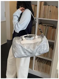 Sac de voyage argenté froissé stylé avec bandoulière blanche pour voyage et sport.