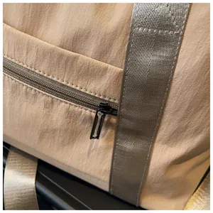 Detailansicht der beigen Reisetasche mit strapazierfähiger Stoffstruktur und starkem Gurt.