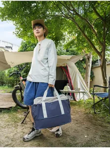 Detailed outdoor camping scene showing the color-block travel duffel bag with handles.