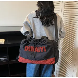 Detail view of the black and red travel duffel bag showing texture, straps, and front lettering.