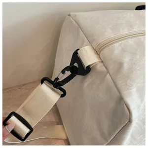 Vue rapprochée détaillée de la sangle réglable et des boucles en plastique du sac de voyage.