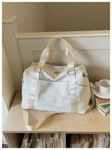 Stylish white star-printed travel duffel bag with shoulder strap and front pocket design.