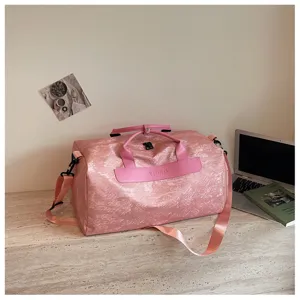 Détail de sac de voyage rose avec patch en cuir rose et tissu imperméable résistant.