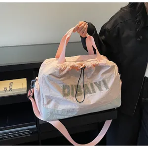 Closeup detail of the pink travel duffel bag with stylish front lettering and strap.