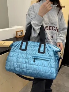 Shiny metallic blue quilted travel duffel bag with black handles, stylish gym tote main view.