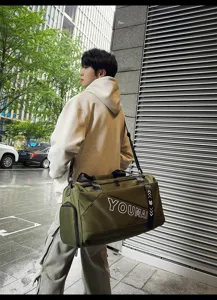 Outdoor scene showing a large-capacity green travel duffel bag worn by an Asian male model.