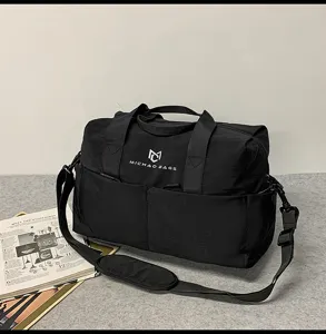 Detail view of durable black travel duffel bag with shoulder strap and custom front logo.