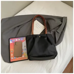Minimalist black shoulder bag detail, stylish brown handles and daily commuter tote design features.