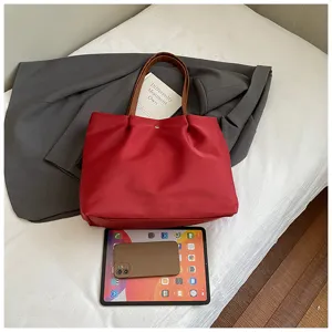 Red solid color tote bag detail showing large capacity with tablet and phone props.