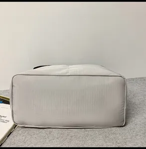 Bottom detail of light grey fabric travel duffel bag showing durable grid fabric texture.