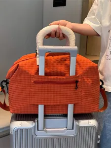 Orange plaid travel duffel bag with luggage sleeve and shoulder strap for commute and trip.