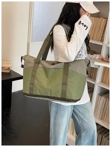 Detailed view of large capacity canvas travel bag with green grid pattern and double handles.