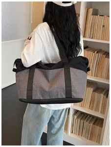 Detailed view of large capacity grid travel duffel bag carried by model for outdoor and gym.
