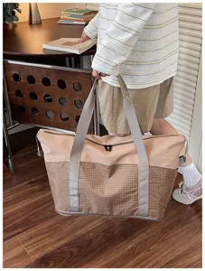 Detail view of the large capacity travel duffel bag featuring grid pattern and sturdy grey straps.