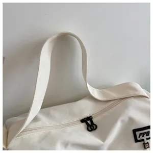 Close-up detail of white canvas travel gym bag, featuring sturdy shoulder strap and double zippers.