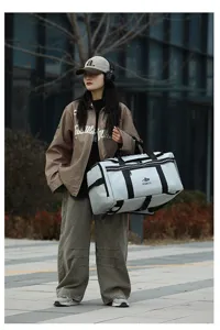 Outdoor travel duffel bag detail showing large capacity, grey fabric and sturdy black straps.