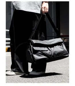 Close-up detail of the black waterproof travel shoulder bag, showing durable fabric and strap.