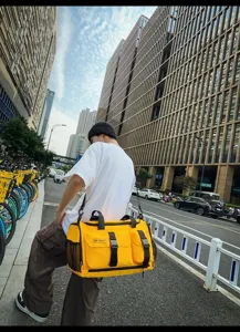 Outdoor street scene detail showing the bright yellow multi-functional travel duffel bag.