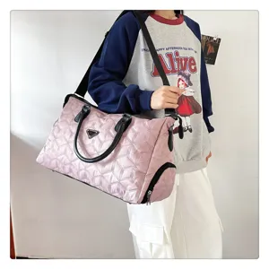 Vue détaillée du sac de voyage matelassé rose avec compartiment à chaussures, porté.