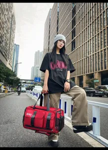 Outdoor street scene detail showing a large red multi-pocket travel gym duffel bag.