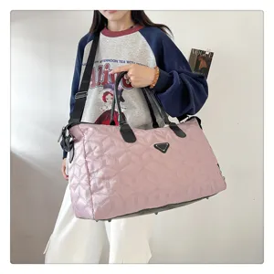 Sac de voyage matelassé rose avec anses, bandoulière et grande capacité de rangement.