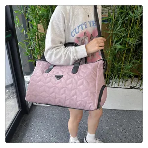 Détail de sac de voyage matelassé rose, grand weekender spacieux avec poignées et sangle.