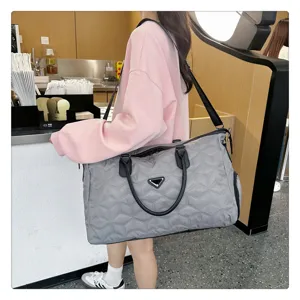 Grand sac de voyage matelassé gris avec bandoulière confortable pour les voyages.
