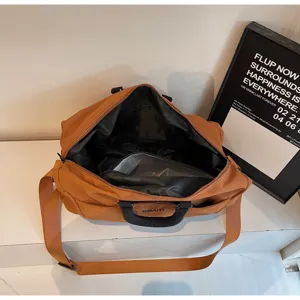 Large capacity brown travel duffel bag detail, casual overnight luggage bag with shoulder strap.