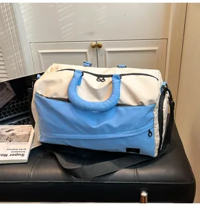 Detailed close-up shot of the color-block travel duffel bag with blue handles on bench.
