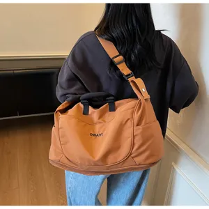 Detail view of the brown large capacity travel duffel bag with shoulder strap and durable fabric.