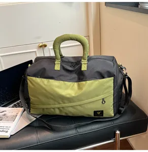 Detailed view of the black and green duffel bag, showing its soft material and front zipper pocket.