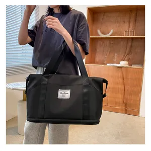 Vue détaillée d'un grand sac de voyage étanche noir avec des poignées très solides.