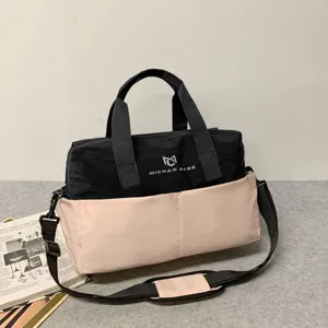 Detail view of the two-tone travel duffel bag with handles and adjustable shoulder strap.