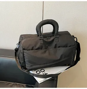 Black travel duffel bag detail, featuring durable fabric, padded handle and shoulder strap.