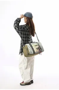 Detail view of the multi-color travel duffle bag with shoulder strap worn by a model.