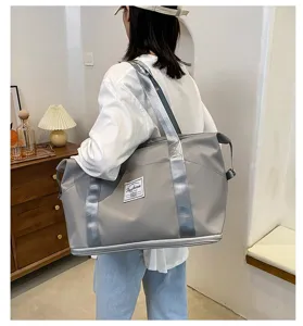 Détail du sac de voyage étanche gris, grand sac de sport avec poignées robustes et pratiques.